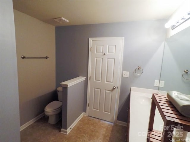 bathroom featuring baseboards, vanity, and toilet