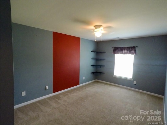 carpeted empty room with a ceiling fan and baseboards