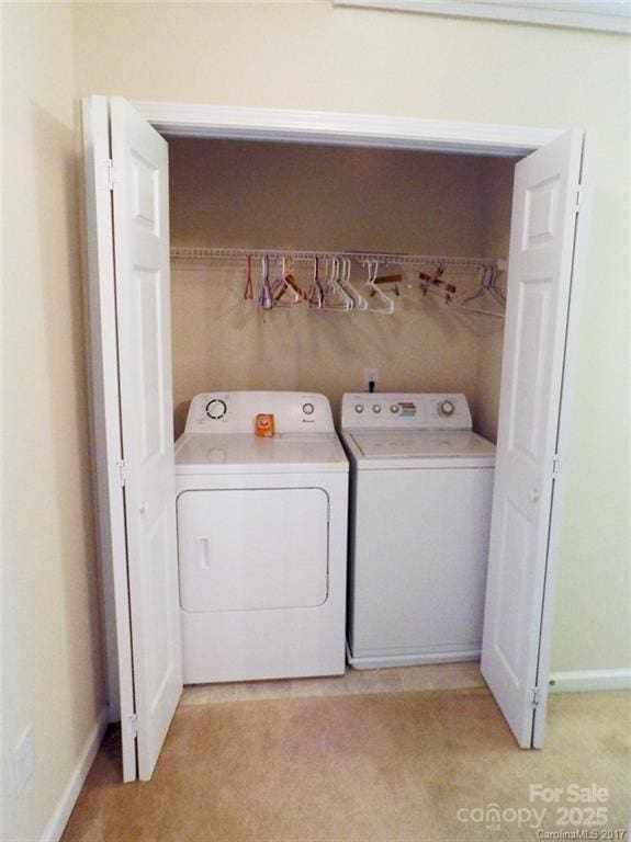 clothes washing area featuring light carpet, washer and clothes dryer, laundry area, and baseboards