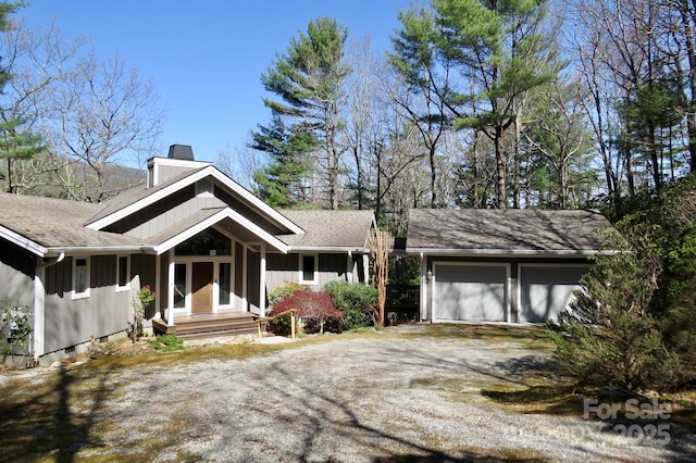 view of front of property with board and batten siding, dirt driveway, an attached garage, and a chimney