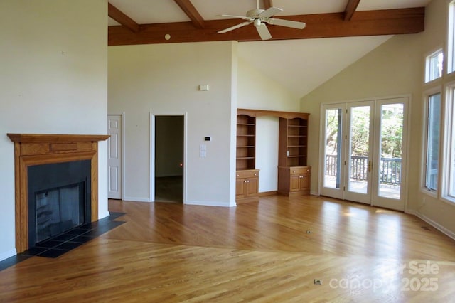 unfurnished living room featuring beamed ceiling, a wealth of natural light, high vaulted ceiling, and wood finished floors