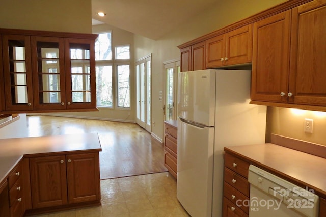 kitchen with white appliances, vaulted ceiling, recessed lighting, light countertops, and brown cabinets