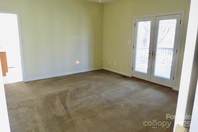 carpeted empty room with a wealth of natural light, french doors, baseboards, and visible vents