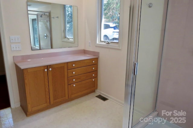 full bath featuring an enclosed shower, vanity, baseboards, and visible vents