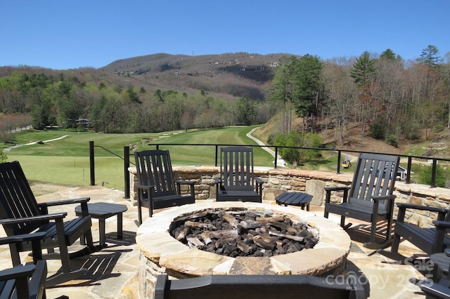 view of patio / terrace featuring an outdoor fire pit, a forest view, and golf course view