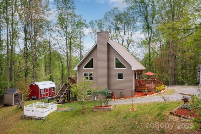 exterior space with a deck, an outbuilding, a garden, and a storage unit