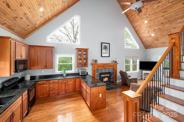 kitchen with a tile fireplace, wooden ceiling, high vaulted ceiling, black appliances, and a peninsula