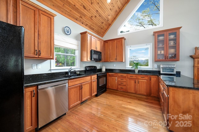 kitchen with brown cabinetry, a sink, light wood-style floors, and black appliances