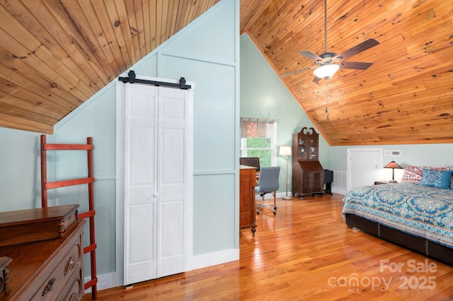 bedroom with a barn door, wood ceiling, wood finished floors, and vaulted ceiling