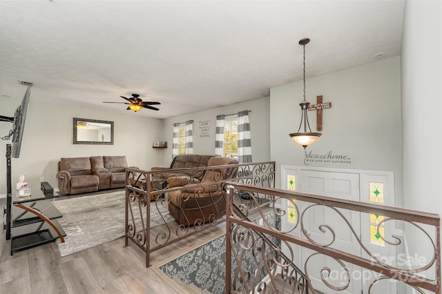 living area with visible vents, ceiling fan, and wood finished floors