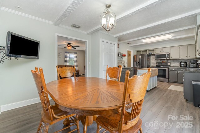 dining room with crown molding, visible vents, baseboards, and light wood finished floors