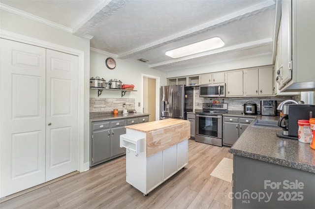 kitchen with appliances with stainless steel finishes, crown molding, gray cabinetry, butcher block countertops, and decorative backsplash