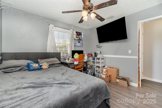 bedroom featuring ceiling fan, baseboards, visible vents, and wood finished floors