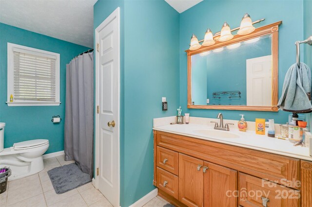 bathroom featuring toilet, tile patterned floors, vanity, and baseboards