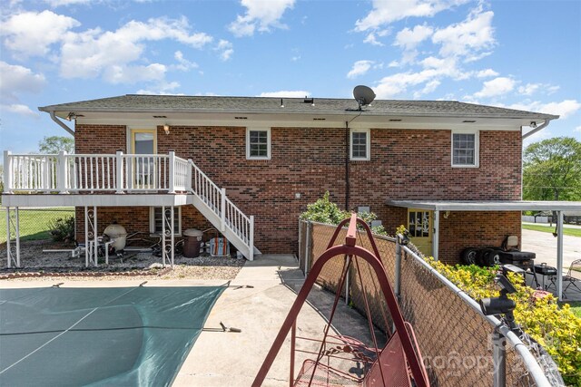 rear view of house featuring stairs, brick siding, fence, and a patio