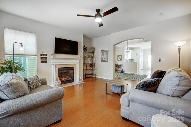 13610 Aldenbrook Dr, Huntersville, NC 28078 - living area featuring light wood-style flooring, a ceiling fan, arched walkways, and a fireplace