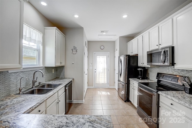13610 Aldenbrook Dr, Huntersville, NC 28078 - kitchen with appliances with stainless steel finishes, a sink, light tile patterned floors, white cabinetry, and decorative backsplash