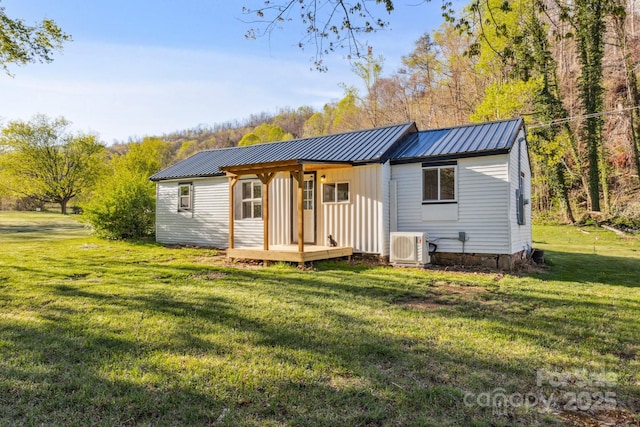 rear view of property featuring a yard, central AC, and metal roof