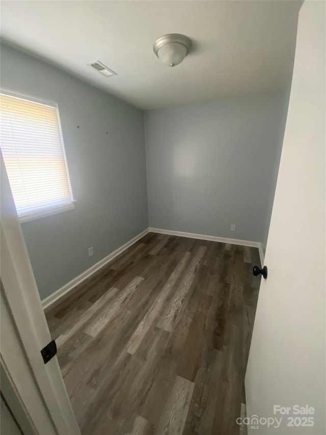 unfurnished room featuring dark wood-style flooring, baseboards, and visible vents
