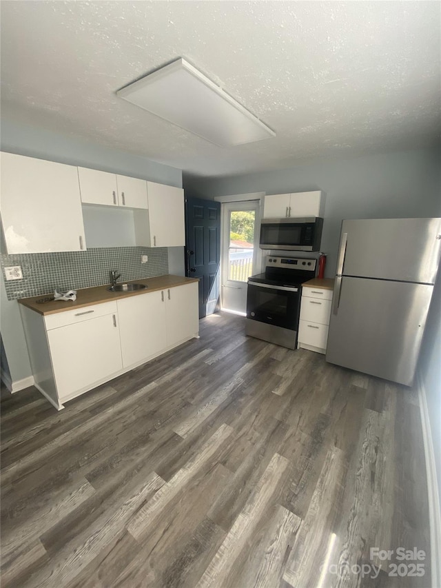 kitchen with white cabinets, tasteful backsplash, dark wood-style flooring, and appliances with stainless steel finishes