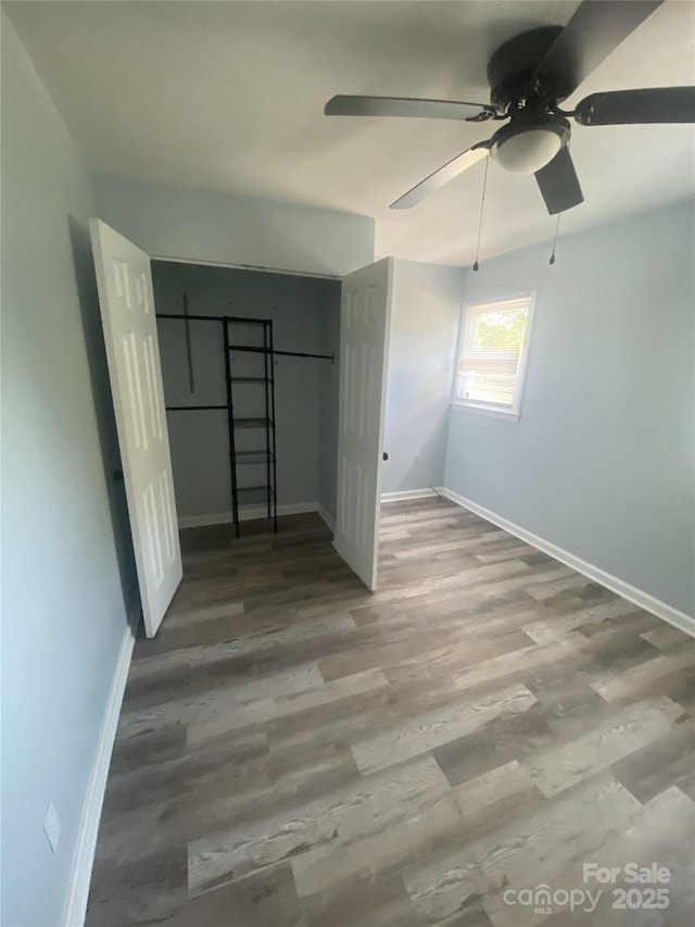 unfurnished bedroom featuring a closet, baseboards, a ceiling fan, and wood finished floors