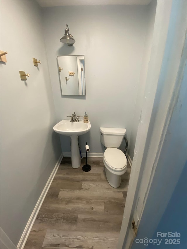 bathroom featuring baseboards, toilet, and wood finished floors