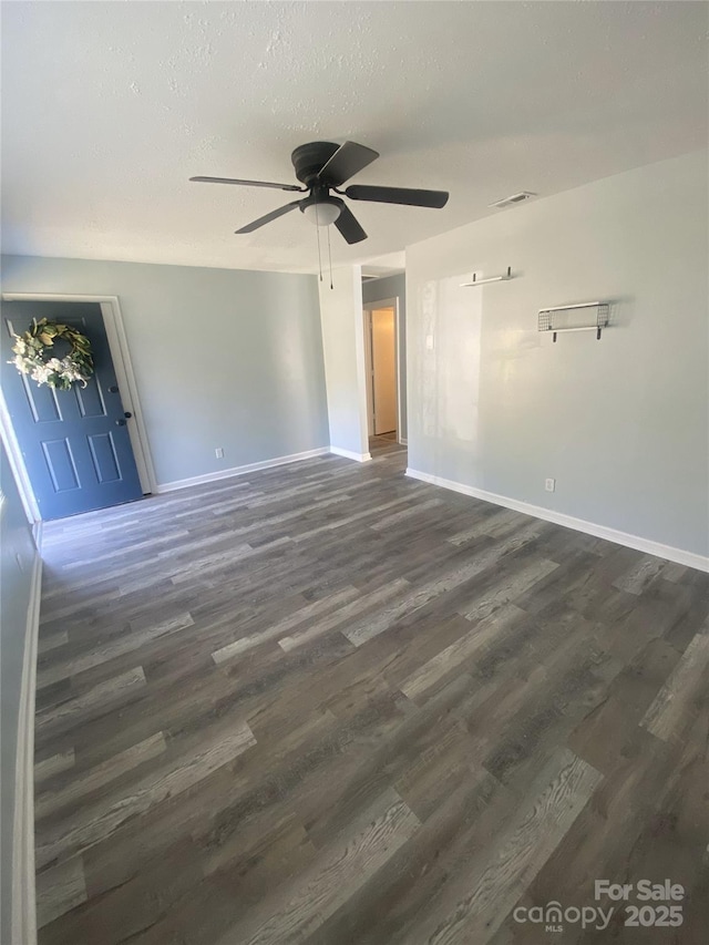 spare room with visible vents, ceiling fan, baseboards, and dark wood-style floors