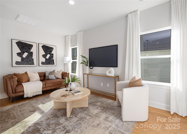 living area featuring visible vents, baseboards, recessed lighting, and wood finished floors