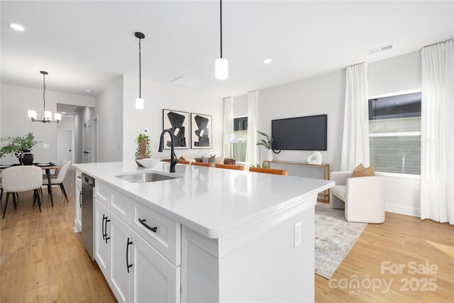kitchen with light wood finished floors, a sink, visible vents, and a notable chandelier