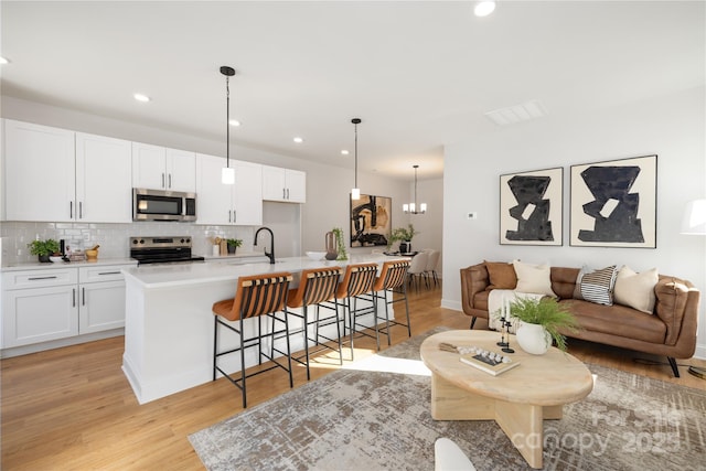 kitchen featuring tasteful backsplash, white cabinets, appliances with stainless steel finishes, and a breakfast bar