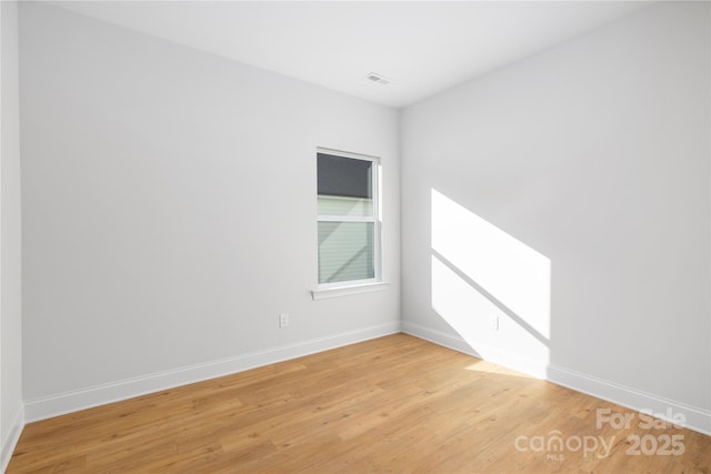 empty room with light wood-style floors, baseboards, and visible vents