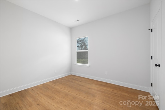 unfurnished room with light wood-style floors, visible vents, and baseboards