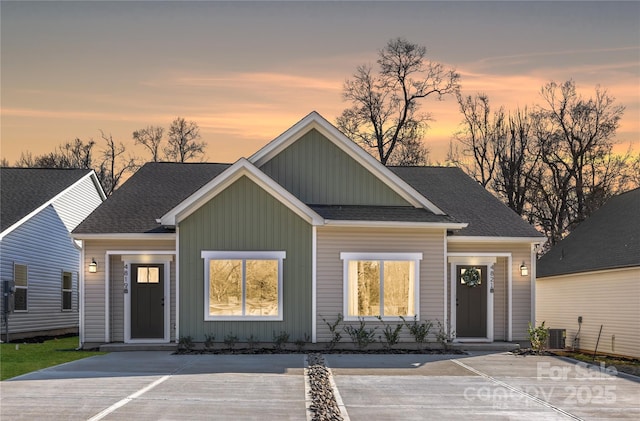view of front of house featuring board and batten siding, roof with shingles, and cooling unit