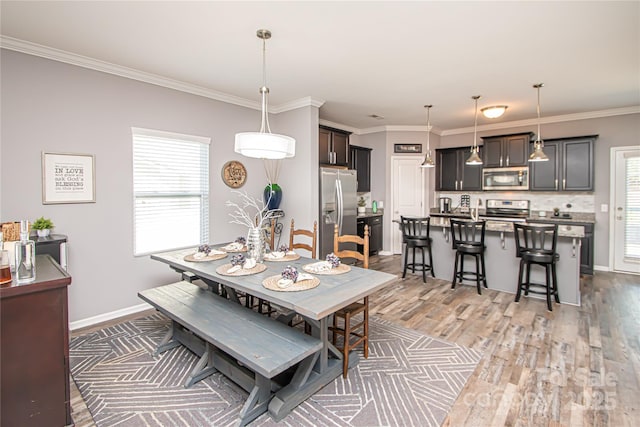 dining space featuring baseboards, crown molding, and wood finished floors