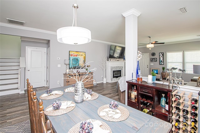 dining area with a ceiling fan, a glass covered fireplace, wood finished floors, and stairs