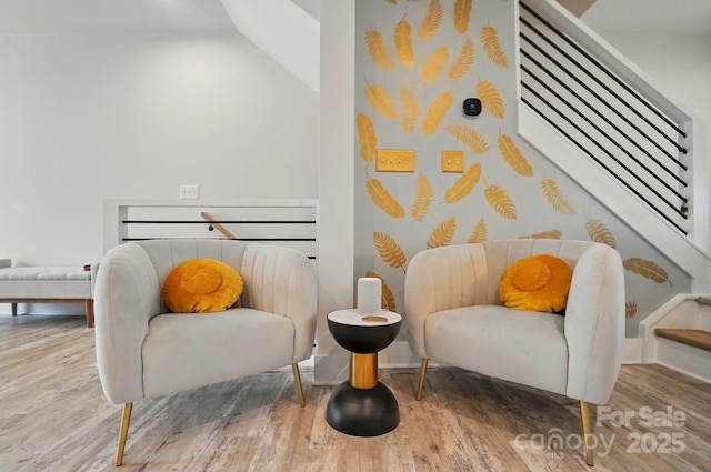 sitting room with stairs and wood finished floors