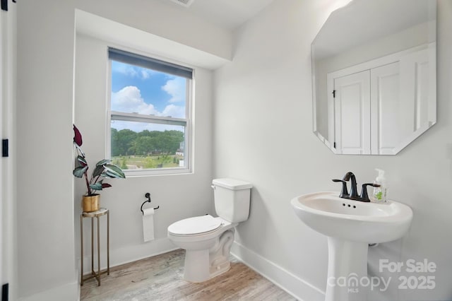 bathroom with baseboards, wood finished floors, and toilet