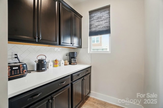 bar with baseboards, decorative backsplash, and light wood finished floors