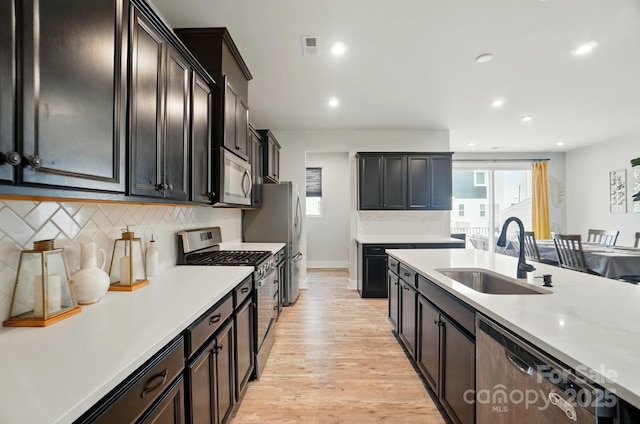 kitchen with a sink, light countertops, light wood-style floors, and stainless steel appliances