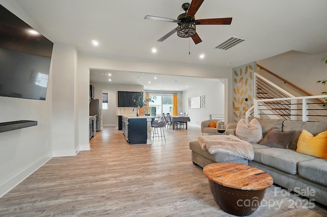 living room featuring light wood finished floors, a ceiling fan, baseboards, recessed lighting, and visible vents
