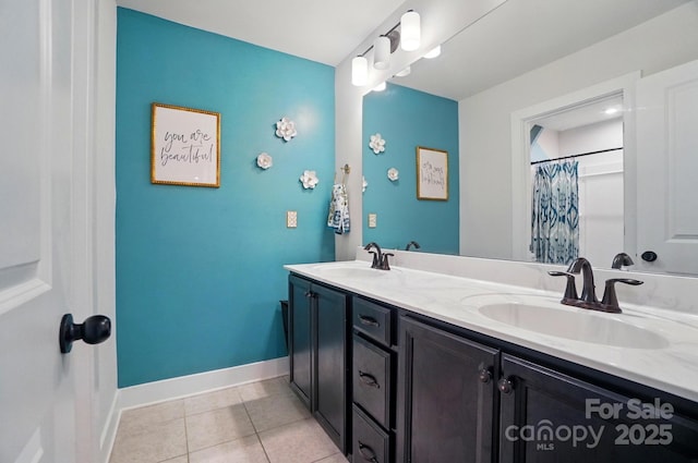 bathroom featuring baseboards, a sink, tile patterned floors, and double vanity