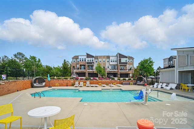 pool with a patio area and fence