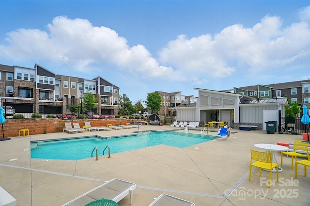 community pool featuring a patio area, fence, and a residential view