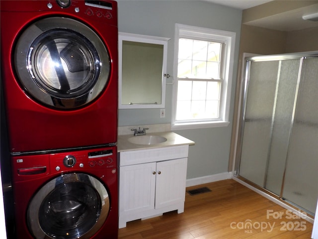 106 Pinetree Dr, Black Mountain, NC 28711 - clothes washing area featuring stacked washer / drying machine, cabinet space, light wood-type flooring, a sink, and visible vents