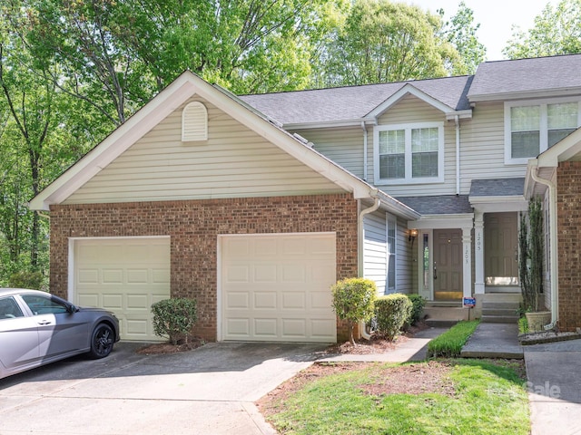 multi unit property with a garage, roof with shingles, and driveway