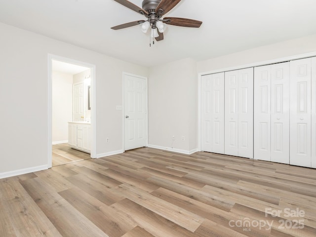 unfurnished bedroom with a closet, baseboards, light wood finished floors, and ensuite bath