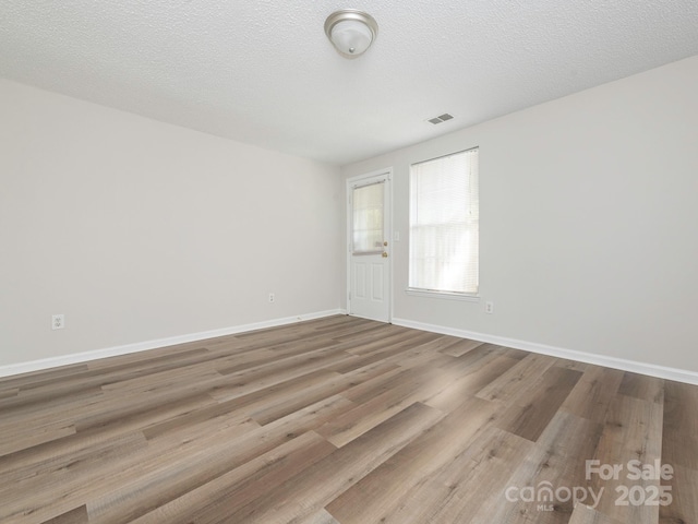 empty room with visible vents, baseboards, and wood finished floors