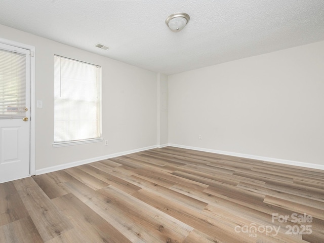 spare room featuring visible vents, baseboards, and wood finished floors