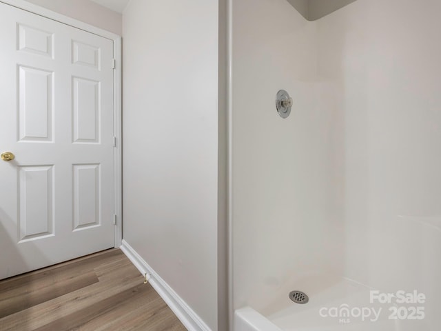 bathroom with a shower, baseboards, and wood finished floors