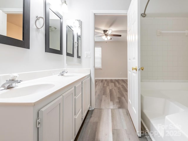 full bath featuring double vanity, a sink, a ceiling fan, and wood finished floors